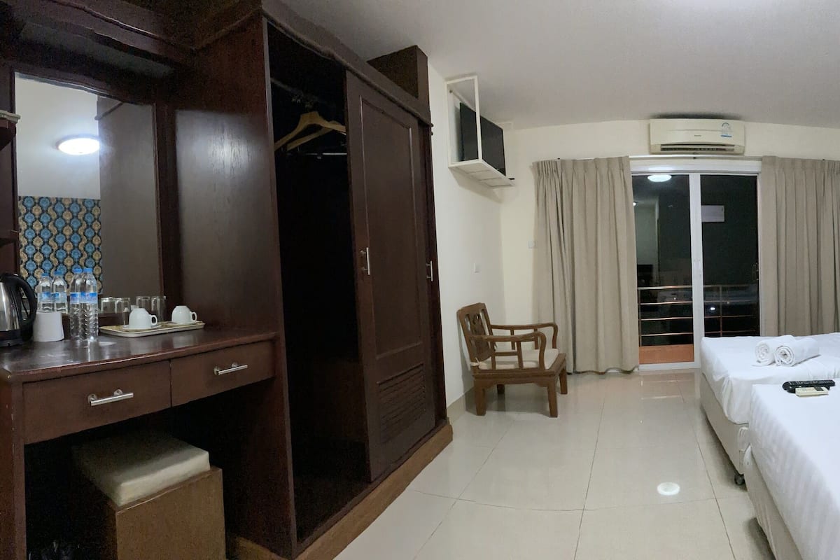 Une chambre d’hôtel comprenant un lit, un bureau avec un miroir, une chaise et une armoire.