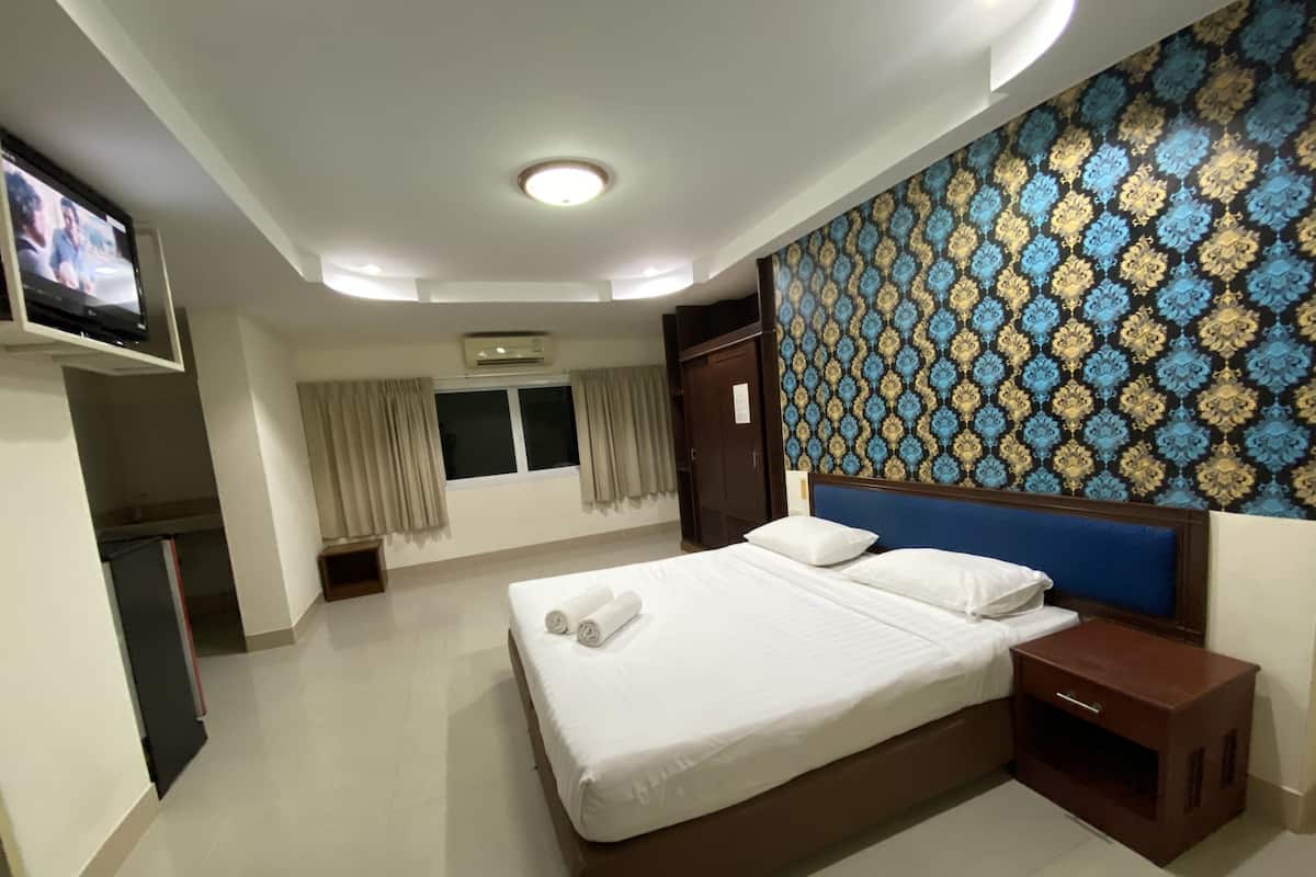 Une chambre d’hôtel avec un grand lit, une télévision, une armoire et un mur décoré d’un motif.