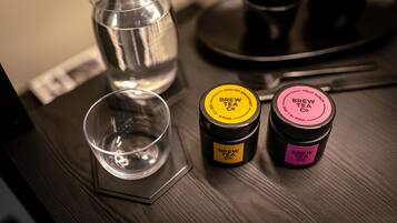 A table with a glass of water, a tea cup, and two containers of Brew Tea Co. tea.