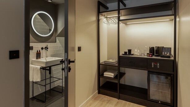 A modern bathroom with a round mirror, a sink, and a built-in oven. - THE ADAMS- Self Check in Hotel (Baden-Baden)