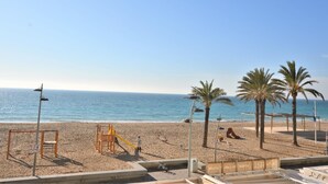 A beach with a playground, palm trees, and a clear sky. - Apartment Lindamar - Calafell (Calafell)