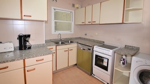 A compact kitchen with a toaster, coffee maker, sink, dishwasher, oven, and a washing machine. - Apartment Lindamar - Calafell (Calafell)