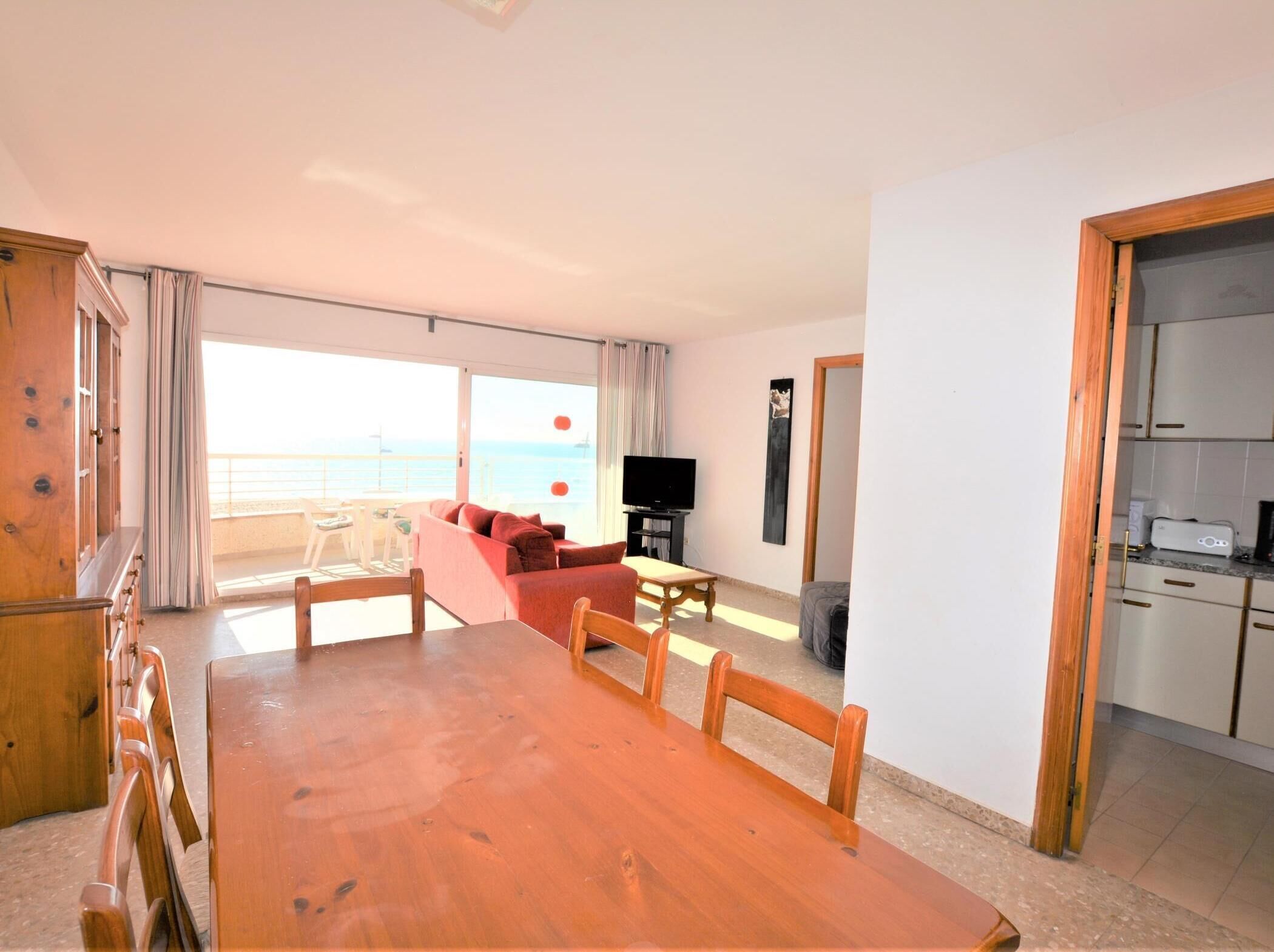 Un salón amplio con una mesa de comedor de madera, un sofá rojo y un televisor.