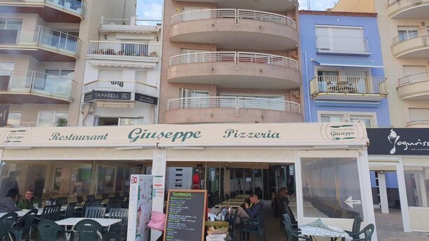Una pizzeria chiamata Giuseppe Pizzeria con posti a sedere all'aperto e una bacheca con il menu.