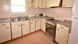 Una cucina con mobili bianchi, un lavello in acciaio inossidabile, un forno a microonde, un tostapane e un forno.