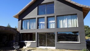 Een twee verdiepingen tellend huis met grote ramen en een schuin dak.