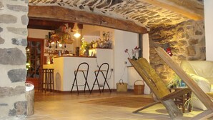 Een rustiek interieur met stenen muren, een bar met krukken en een houten stoel.