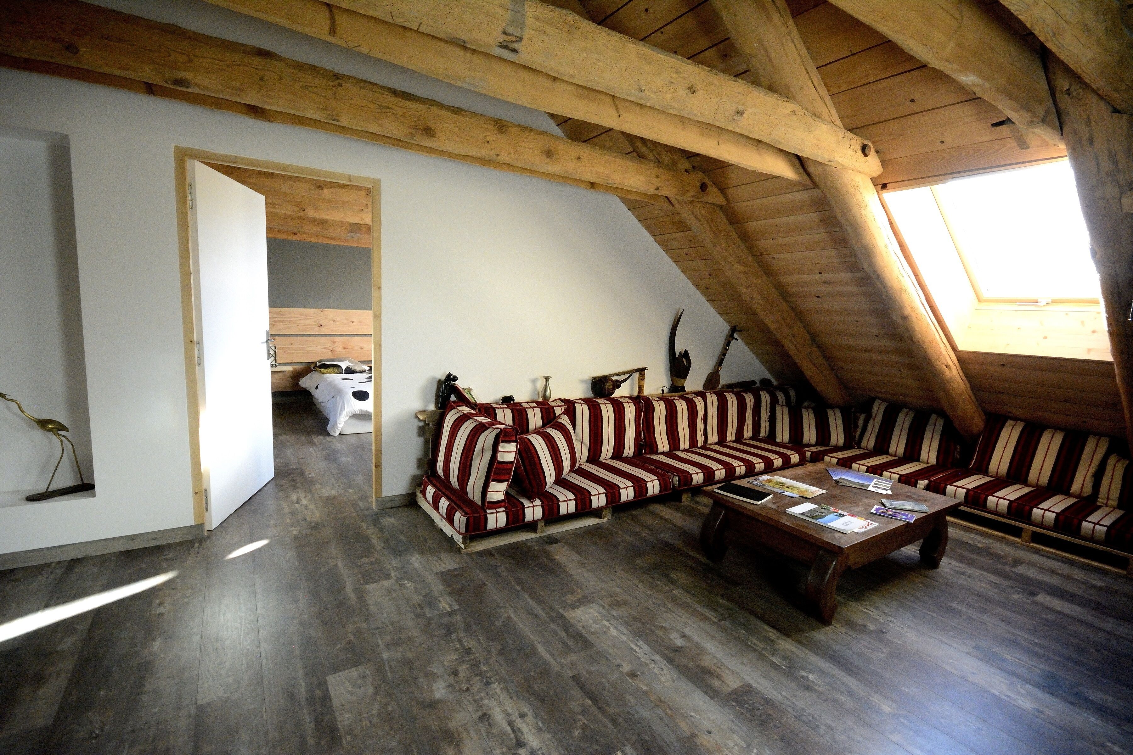 A loft-style room with a wooden ceiling, a sofa set, a coffee table, and a skylight.