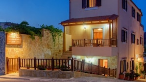 A two-story building with a stone facade, a balcony on the upper floor, and a sign indicating a pension named "Pension Lucy."