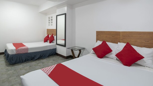 A hotel room with two beds, each with red and white bedding, a wooden headboard, and a large mirror. - OYO 549 Sajj Bldg (Baguio)