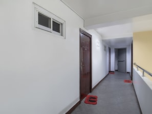 A hallway with a wooden door, a window, and a red mat on the floor. - OYO 549 Sajj Bldg (Baguio)
