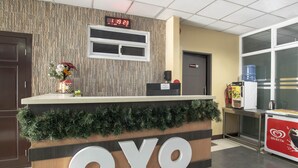 A reception desk with a clock displaying 8:19:23, a sign for restrooms, a water dispenser, and a coffee machine. - OYO 549 Sajj Bldg (Baguio)