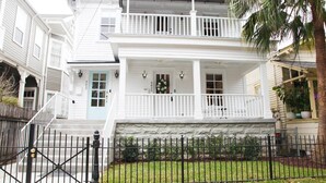A two-story house with a front porch, a stone foundation, and a black metal fence. - Luxe 3BR on Magazine St with private pool & patio. Sleeps 6, walk to cafés, near FQ & Superdome. (New Orleans)