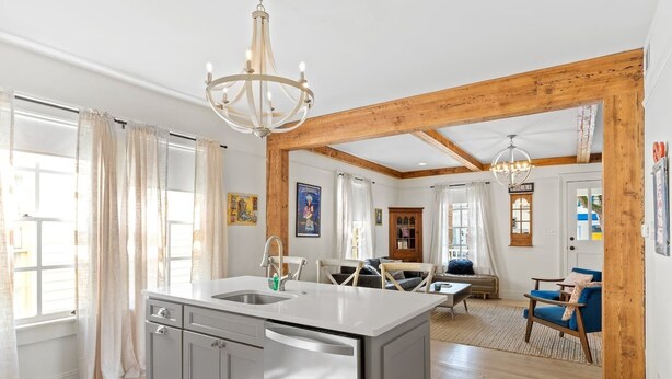A modern kitchen with a central island, wooden beams, and a chandelier. - Luxe 3BR on Magazine St with private pool & patio. Sleeps 6, walk to cafés, near FQ & Superdome. (New Orleans)