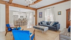 A spacious living room with a blue sofa, a coffee table, and a wooden ceiling. - Luxe 3BR on Magazine St with private pool & patio. Sleeps 6, walk to cafés, near FQ & Superdome. (New Orleans)