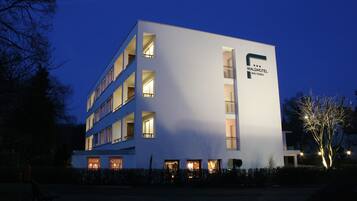 Ein modernes Hotelgebäude mit mehreren Etagen, Balkonen und beleuchteten Fenstern.