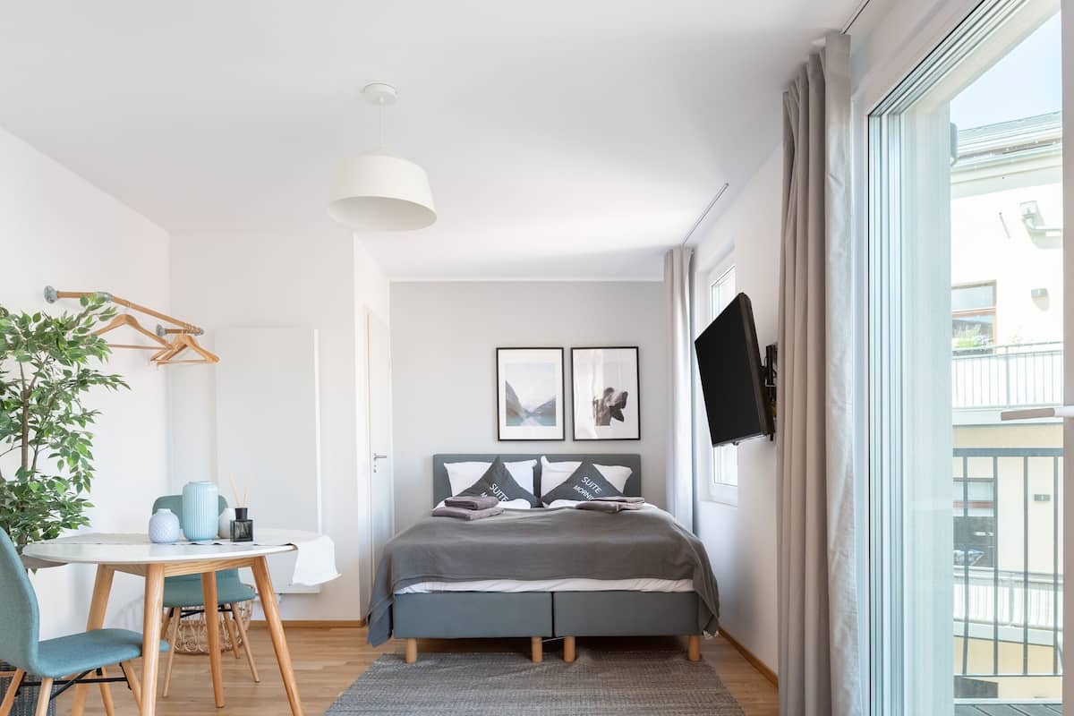A modern bedroom with a bed, a desk, and a large window.