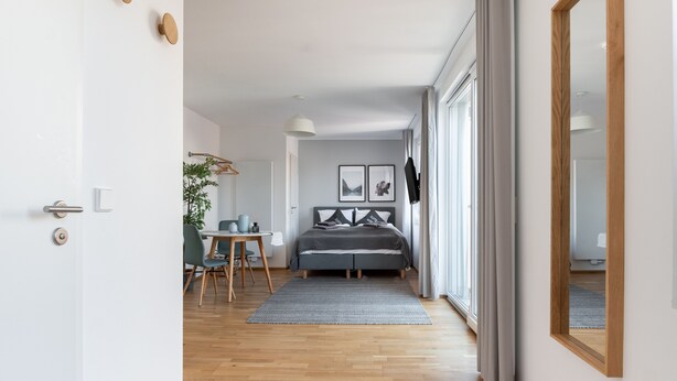 A modern bedroom with a bed, bedside table, and a large mirror. - Limehome Leipzig Jahnallee (Leipzig)