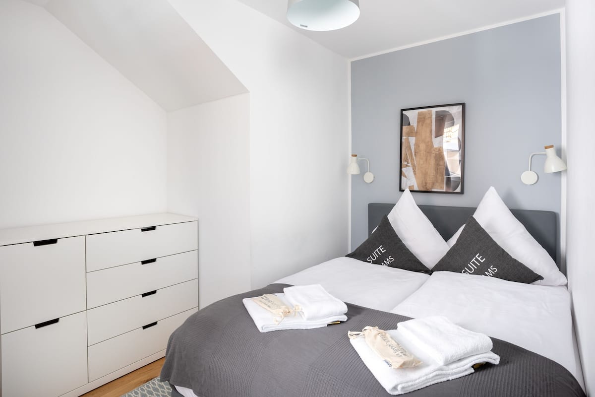 A modern bedroom with a bed, white dresser, and a ceiling light.