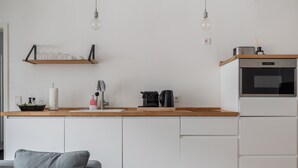 A modern kitchen with white cabinets, a wooden countertop, a coffee maker, and a built-in oven. - Limehome Leipzig Jahnallee (Leipzig)