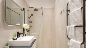 Une salle de bain moderne avec un lavabo blanc, un plan de toilette noir et un grand miroir.