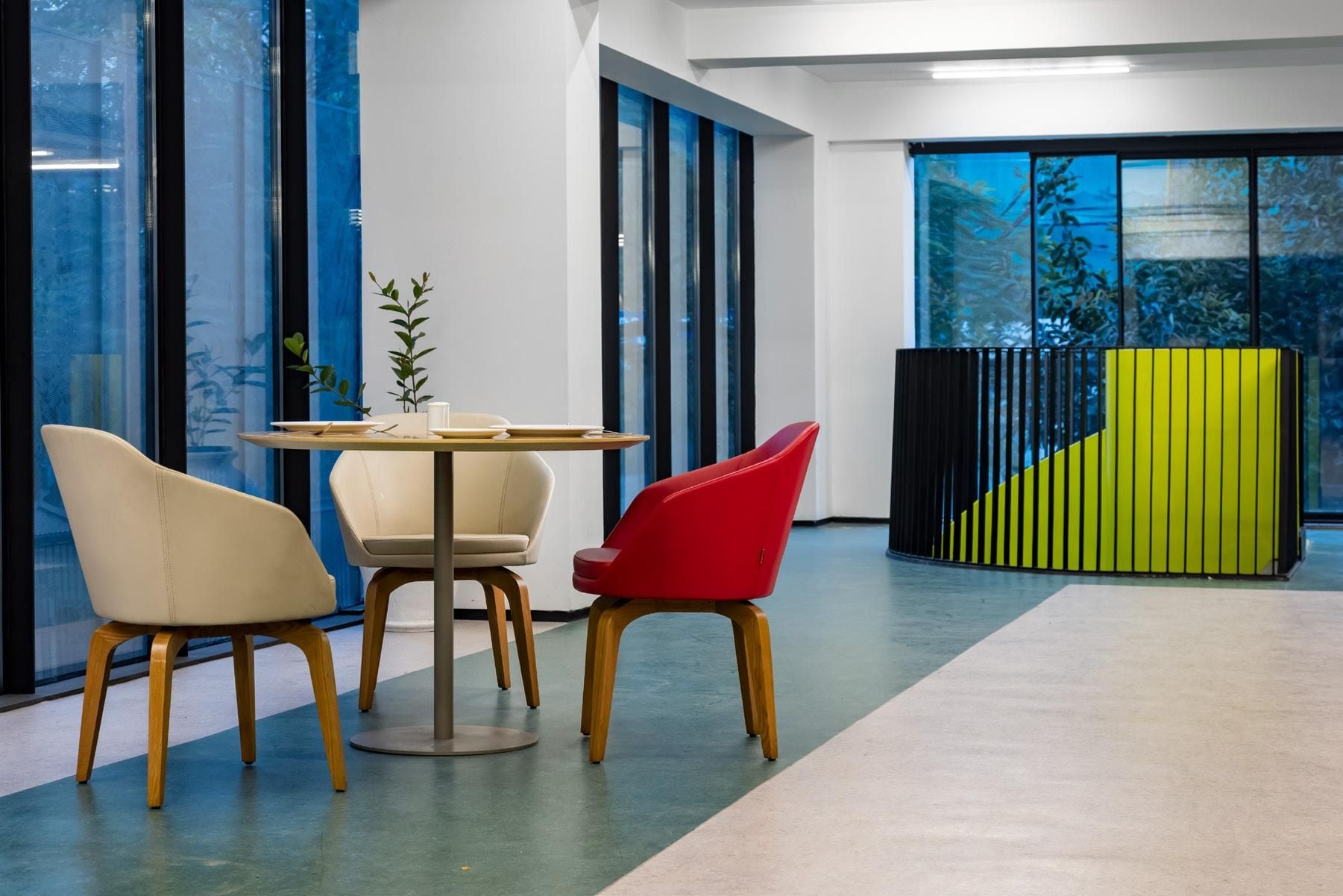 Een modern interieur met een ronde tafel, twee stoelen en een plant.