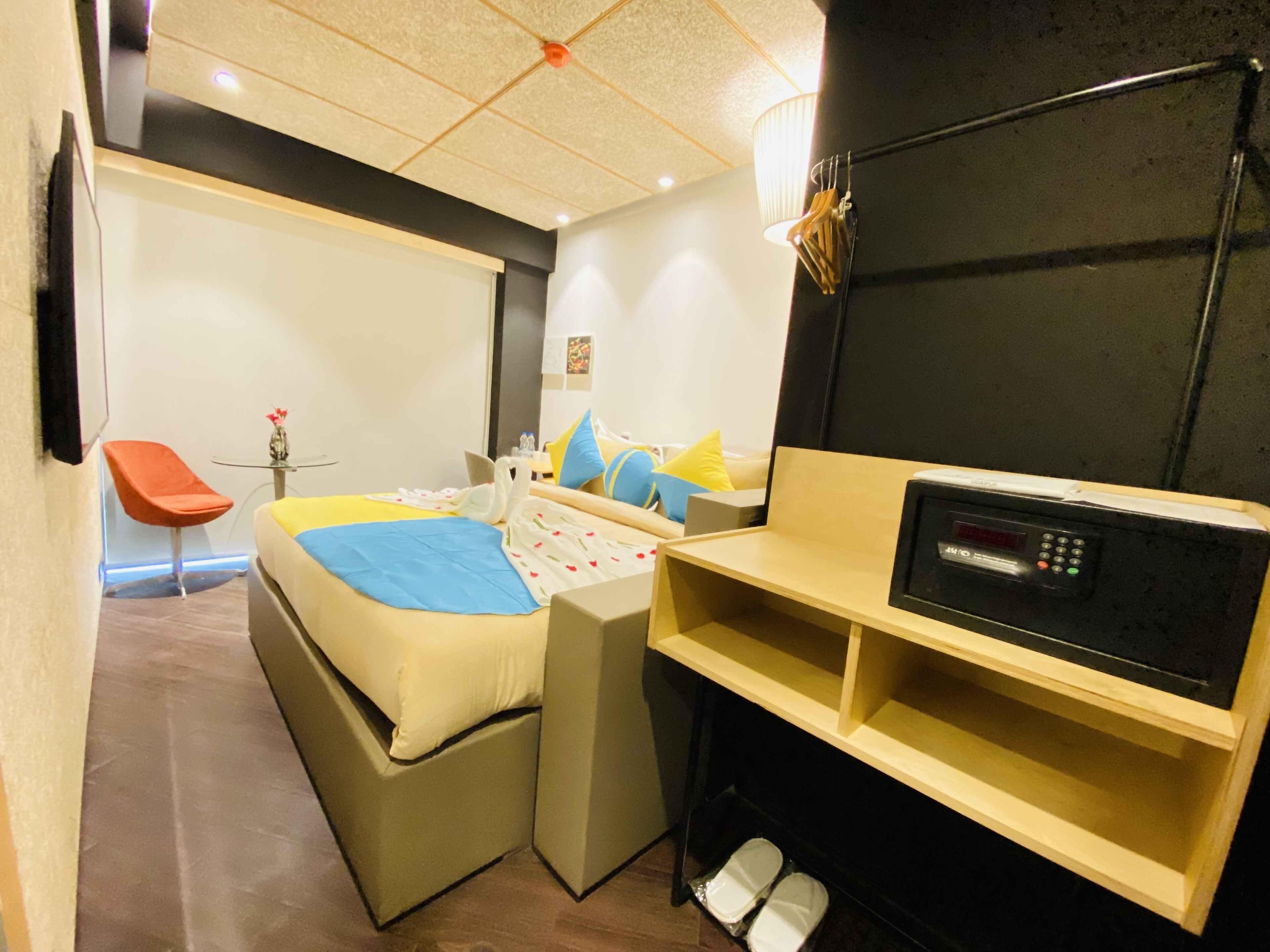 A compact hotel room with a bed, a small desk, a chair, and a TV.
