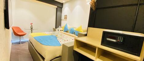A compact hotel room with a bed, a small desk, a chair, and a TV.
