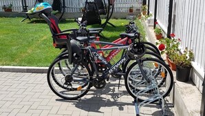 A bicycle parked on a paved surface next to a white fence with potted plants. - Vila 21A (Costinesti)