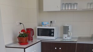 A kitchen with a microwave, coffee maker, and a red kettle on the counter. - Vila 21A (Costinesti)