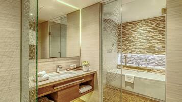 Un baño moderno con ducha envuelta en vidrio, tocador de madera y salpicadero de azulejos.