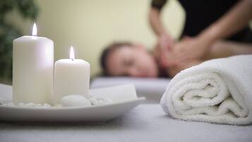 A spa setting with candles, a towel, and a massage table.
