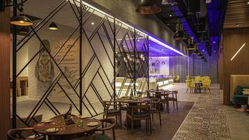 A restaurant with a modern interior, featuring exposed brick walls, a geometric metal partition, and a variety of seating arrangements.