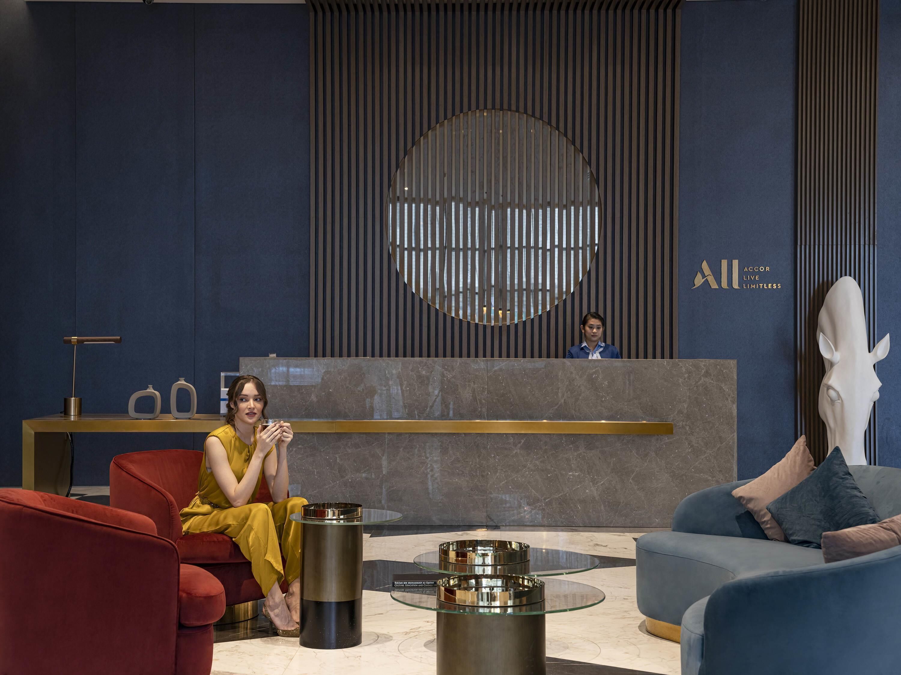 Un área de recepción moderna con un mostrador para recepcionistas, un elemento decorativo circular grande en la pared y muebles contemporáneos.