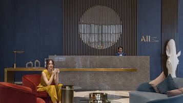 Un área de recepción moderna con un mostrador para recepcionistas, un elemento decorativo circular grande en la pared y muebles contemporáneos.