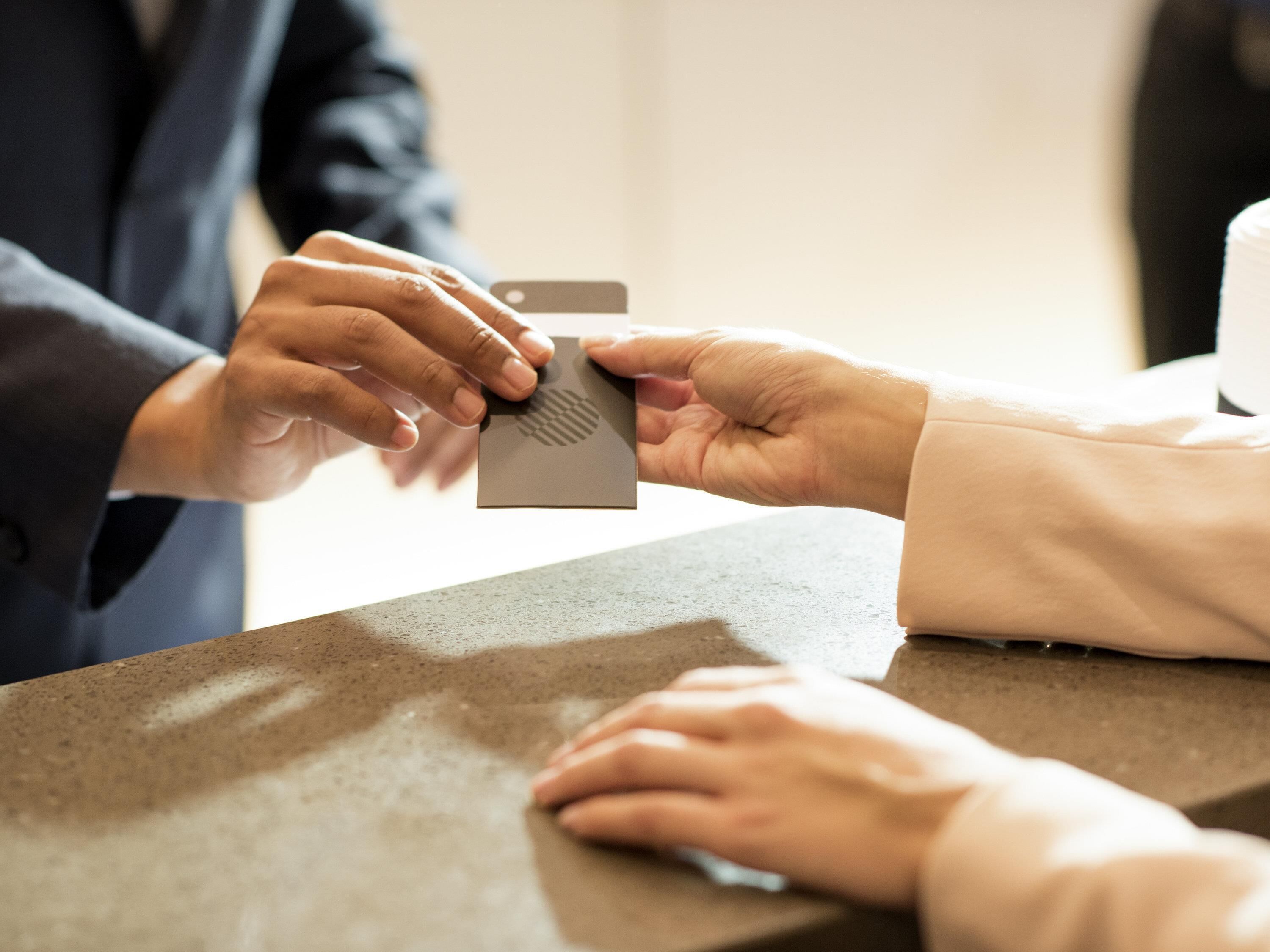 A person handing over a card to another person at a counter.