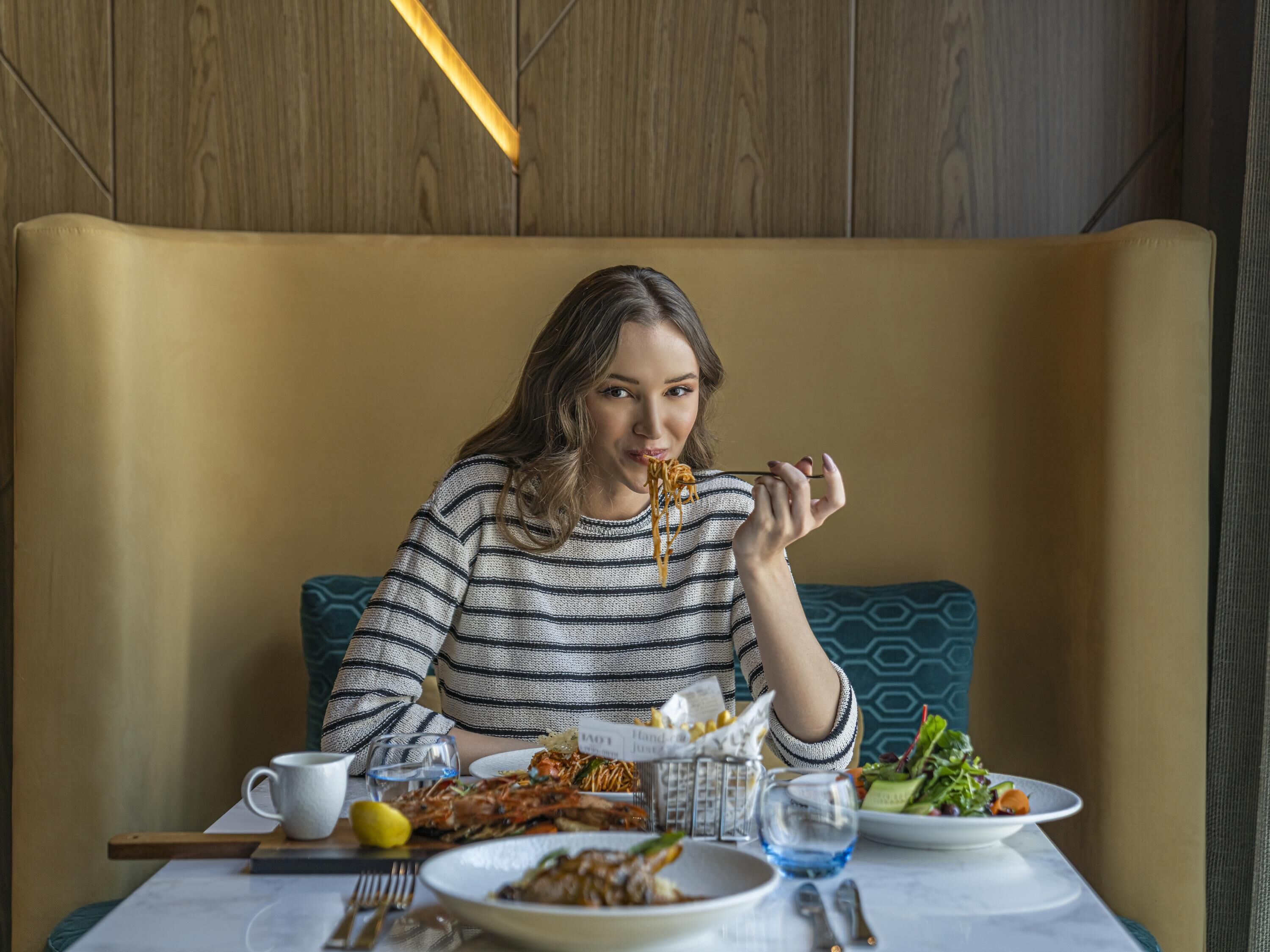 A person seated at a table with a meal, a name card, and a glass of water.