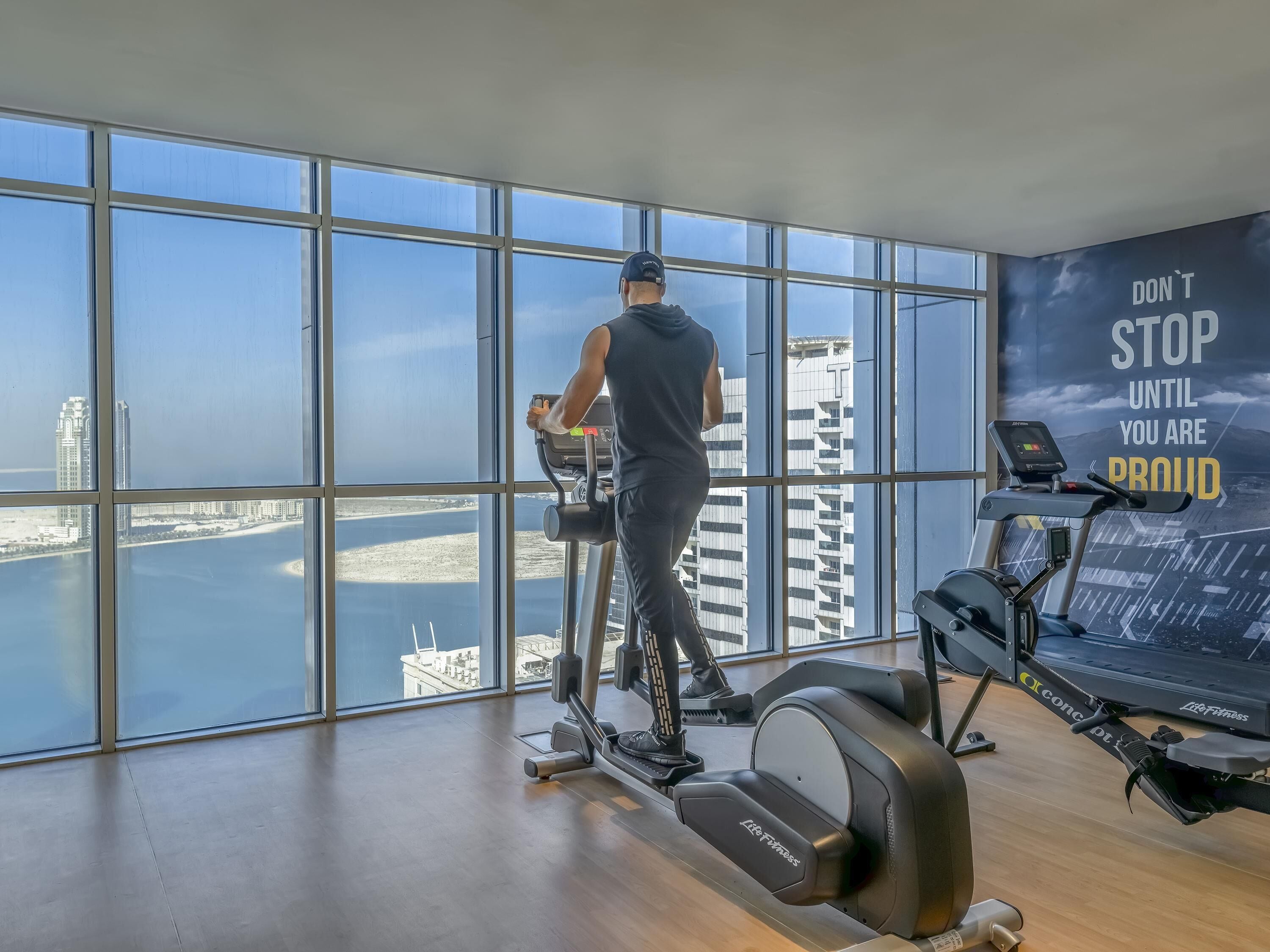 Un gimnasio con amplios ventanales que ofrecen vistas a un paisaje urbano y al agua.