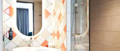 A modern bathroom with a round mirror, a sink, and a shower area.