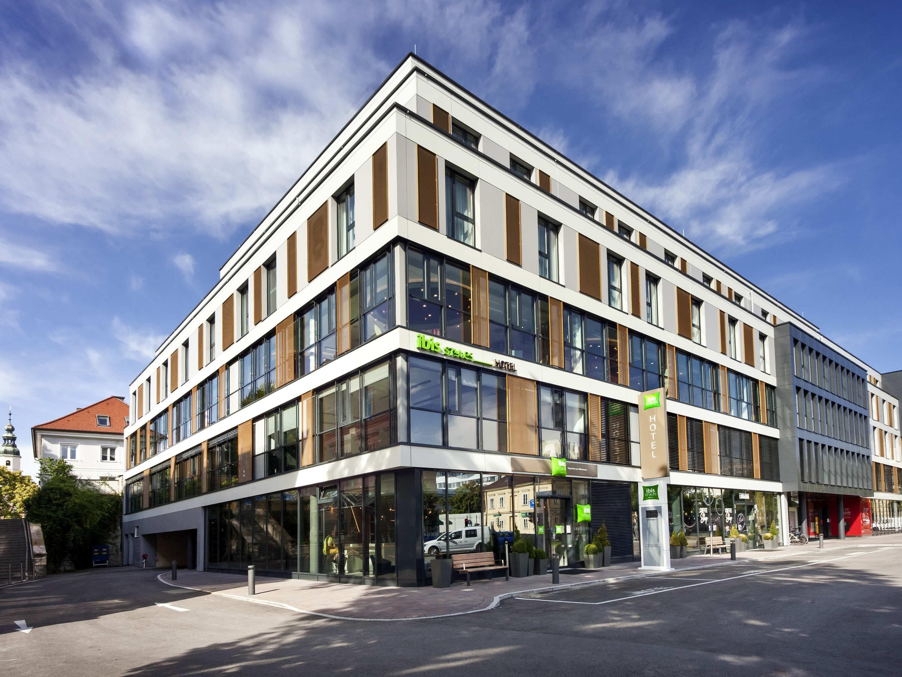 A modern hotel with large windows, a visible entrance, and a clear sky.