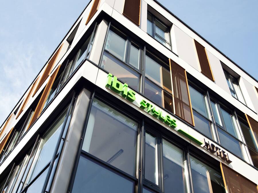 A modern building with large windows and a green sign.