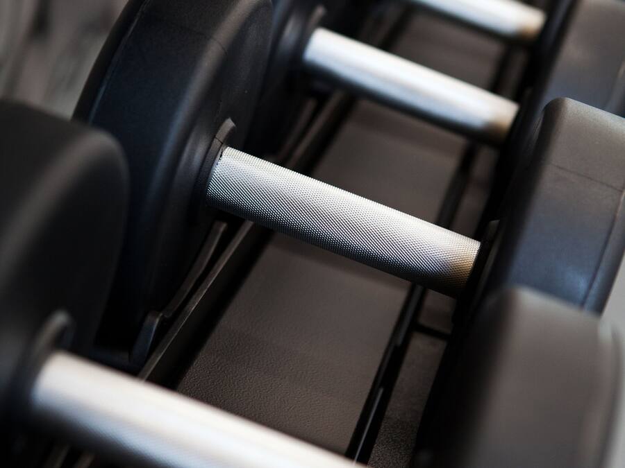 A row of black dumbbells with silver handles on a rack.