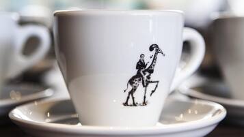 En vit keramisk mugg med ett svart tryck som föreställer en man som rider på en giraff.