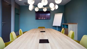 A conference room with a long table, yellow chairs, a whiteboard, and a ceiling light fixture.