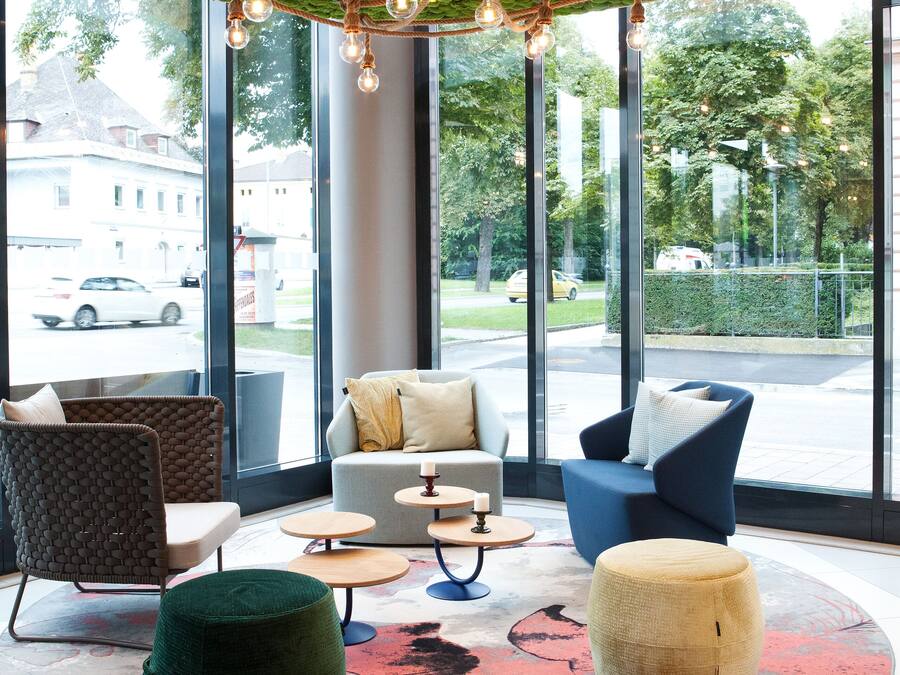 Een modern interieur met een groen plafond, grote ramen en een zithoek met een rond vloerkleed.