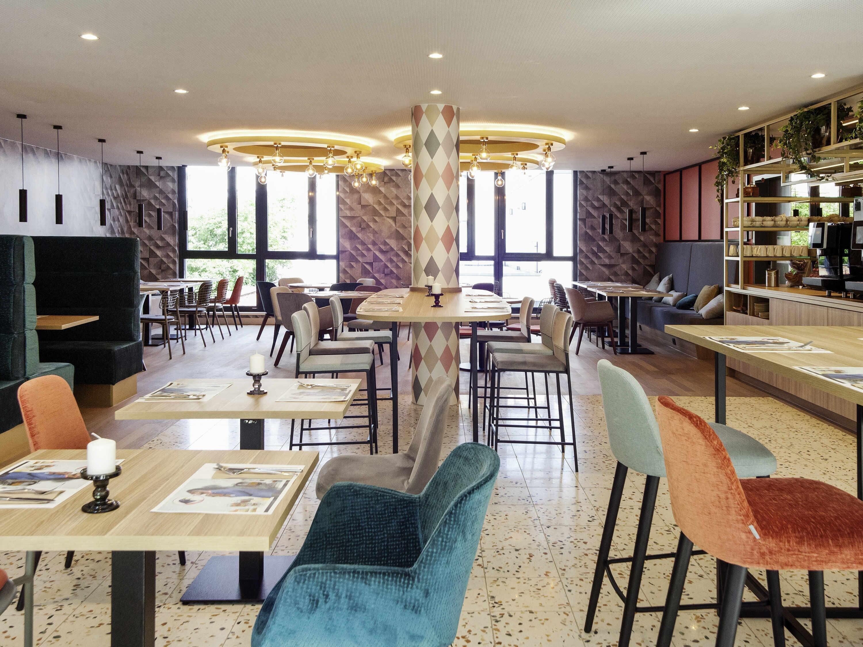 Un restaurante moderno con mesas altas, asientos cómodos y amplios ventanales.