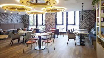 A modern restaurant interior with round tables, chairs, and a unique ceiling design.