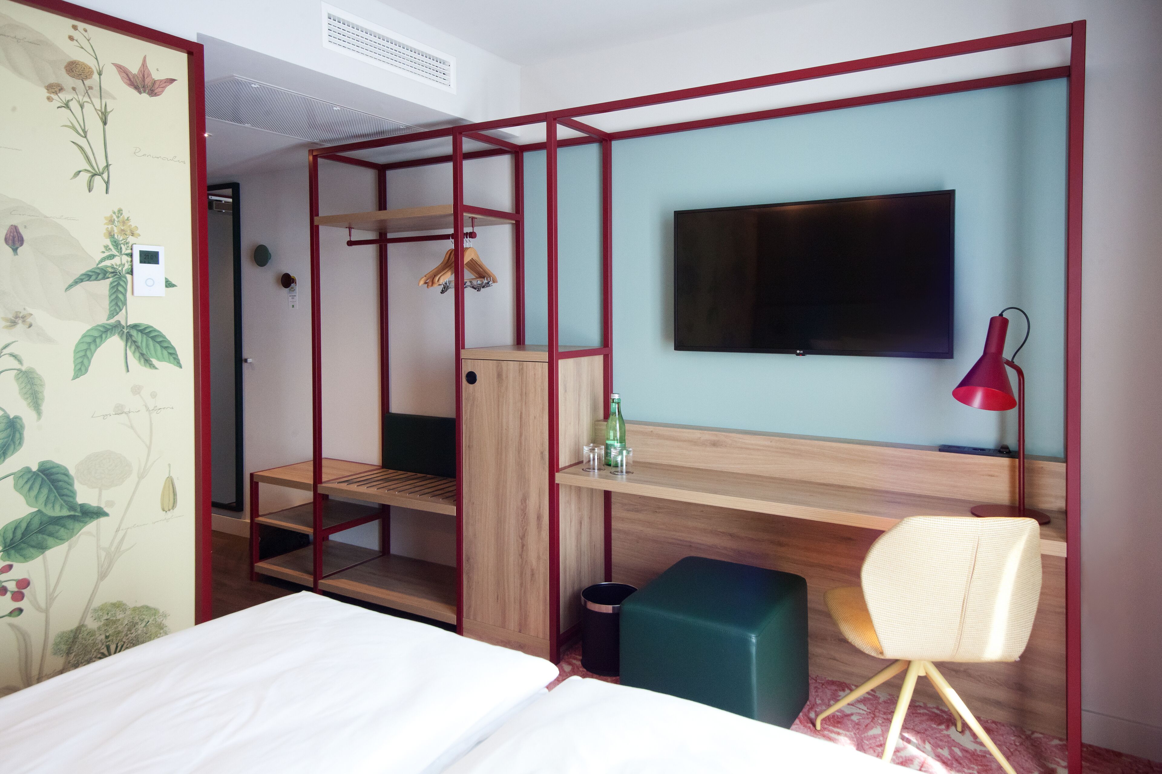 Una habitación compacta con cama, televisión en la pared, escritorio de madera y una silla.