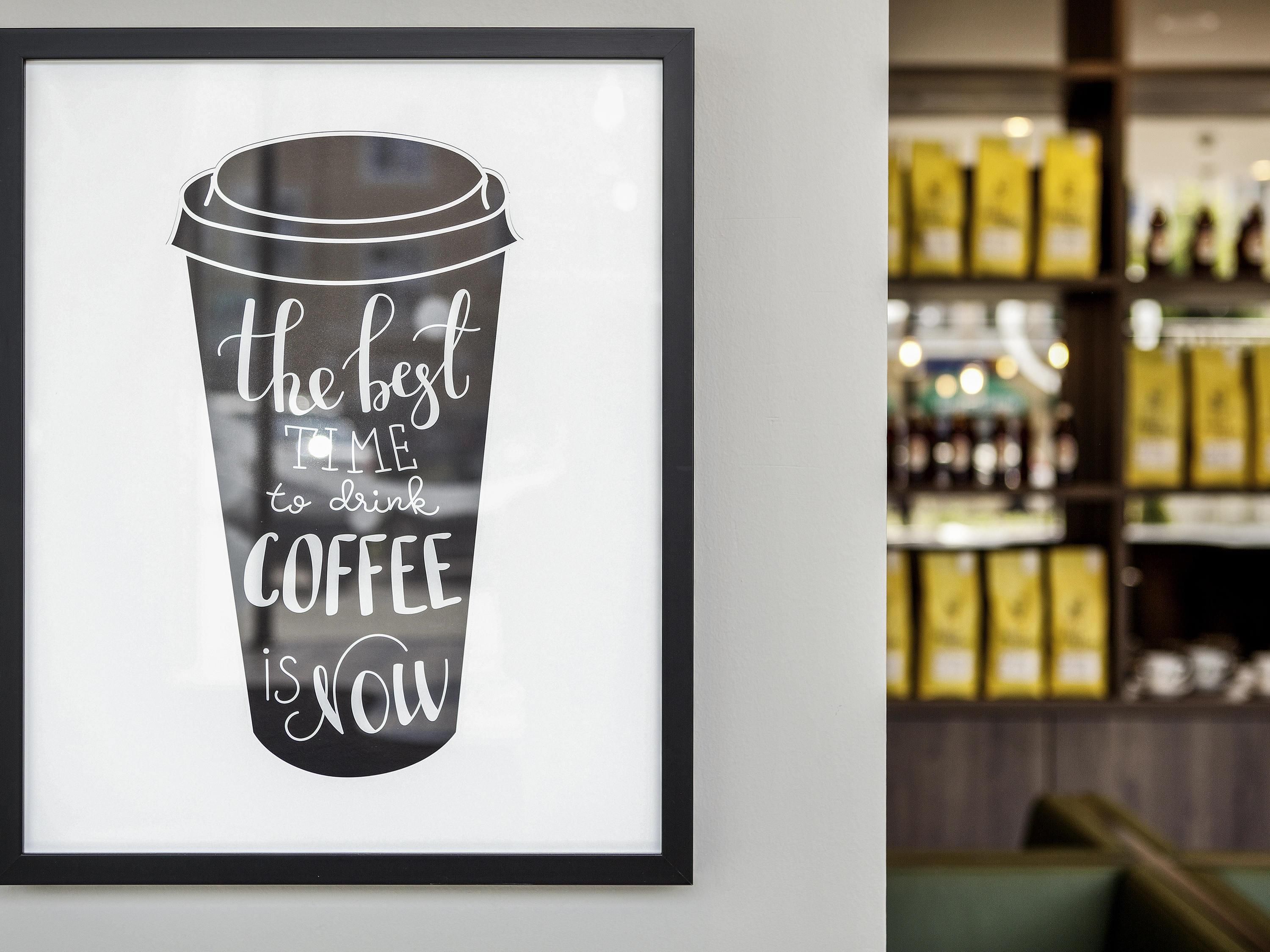 Une tasse à café encadrée, sur laquelle on peut lire : « Le meilleur moment pour boire du café, c’est maintenant », est accrochée à un mur.