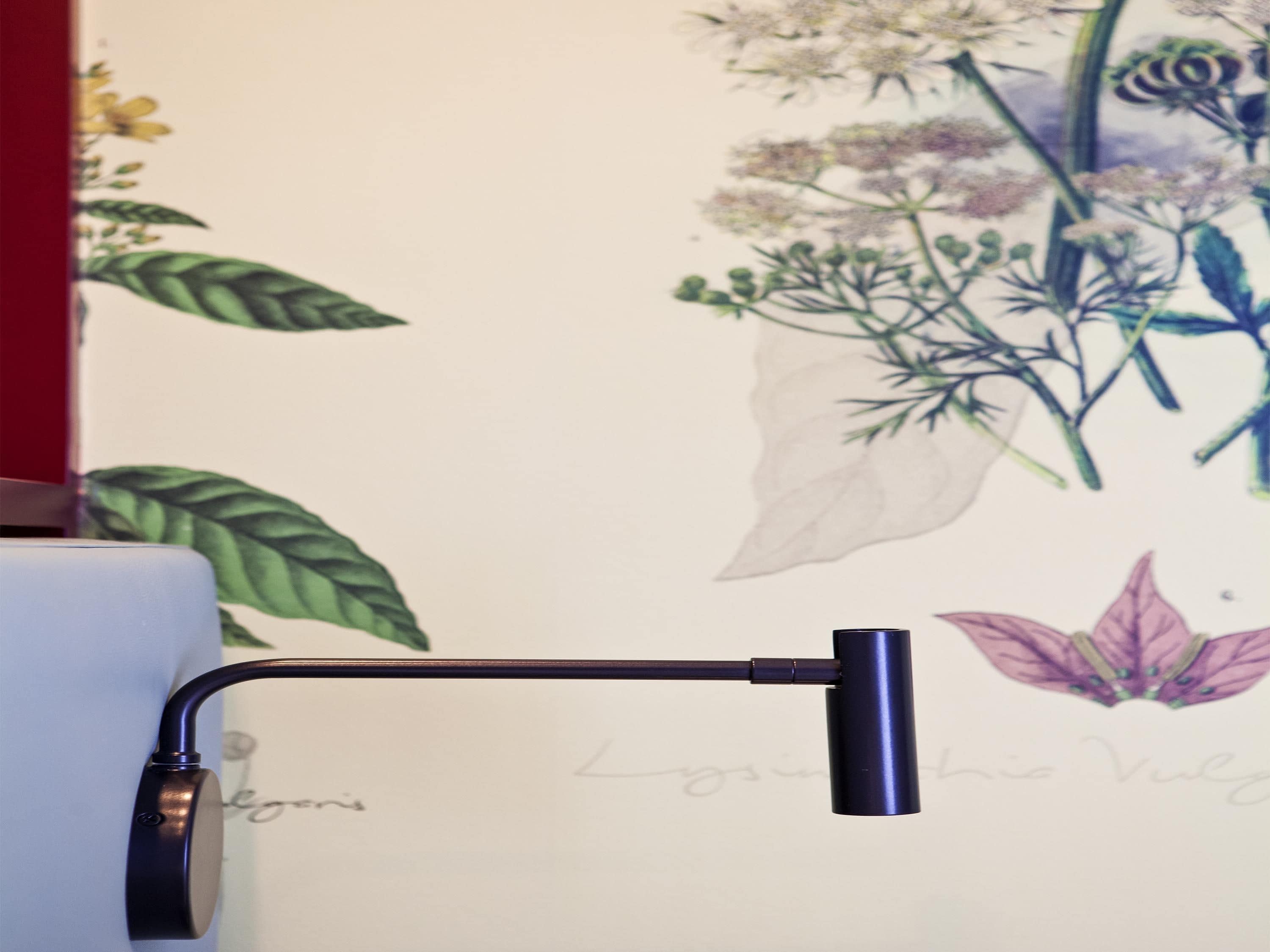 A wall with a floral mural, a black metal object, and a partial view of a white object.